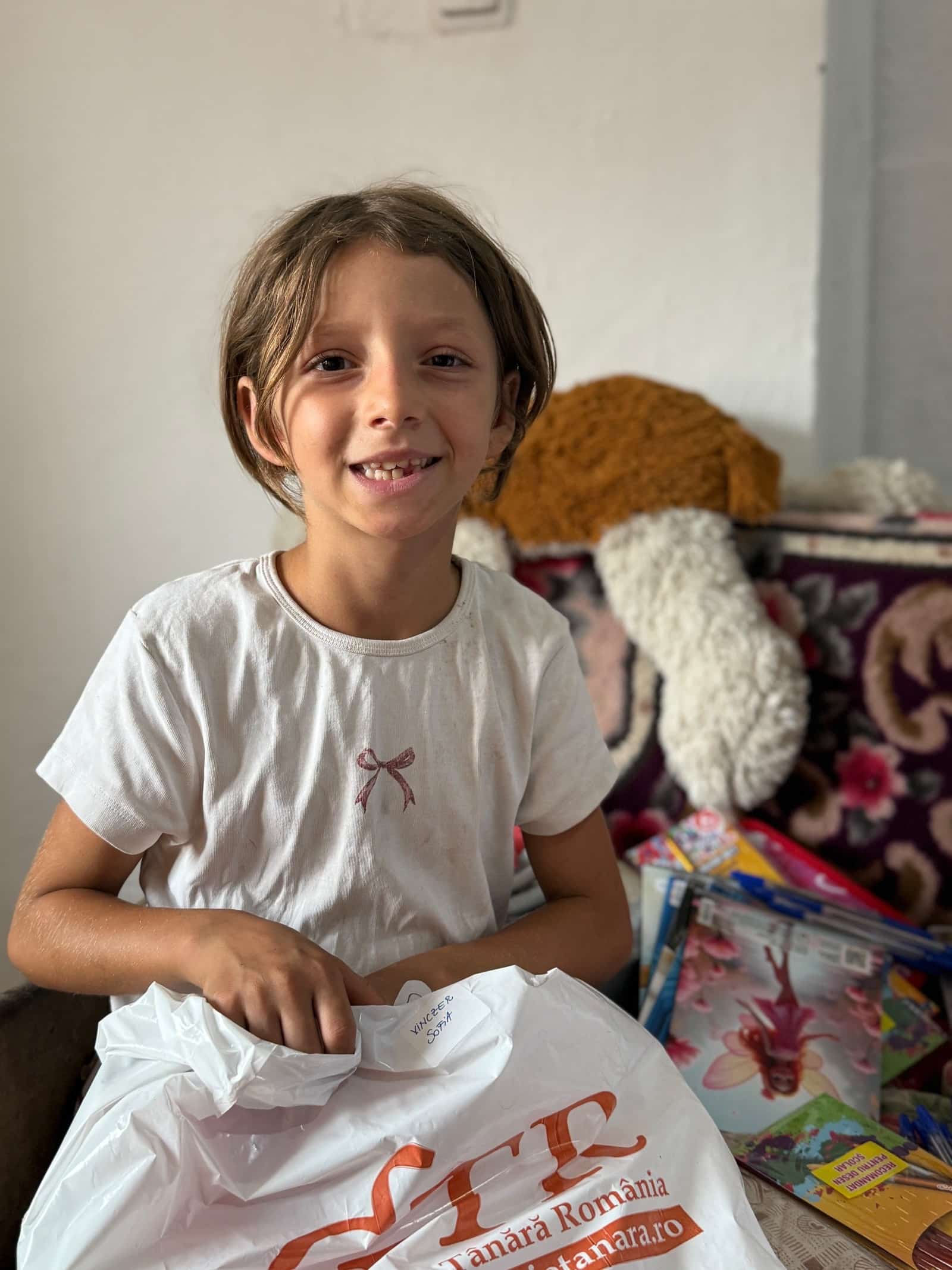 Child holding a bag of school materials.