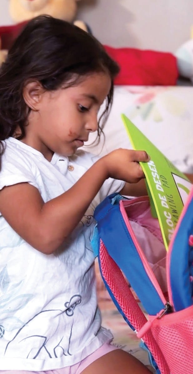 letter-backpack Child looking through school supplies.