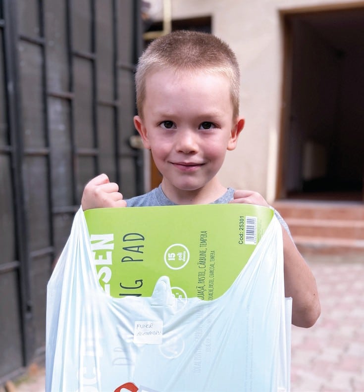 letter-school-supplies Child holding a bag of school supplies.