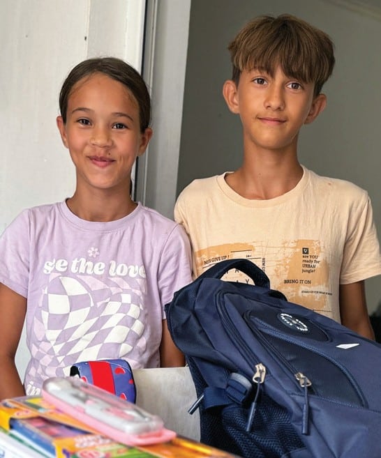 letter-school-supplies Two children beside backpacks and school supplies.