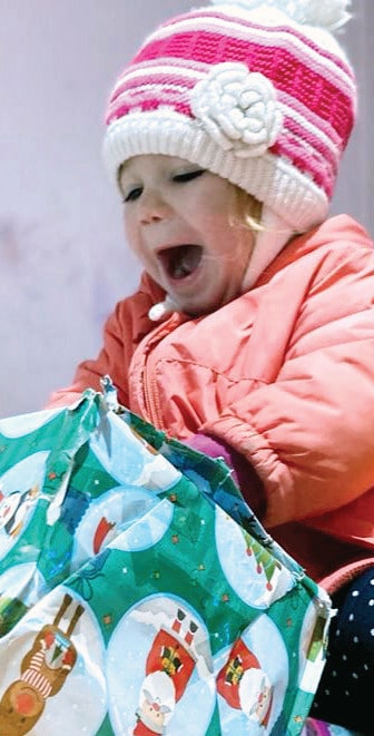 nov1-christmas-gift Child in winter clothing holding a wrapped Christmas gift.
